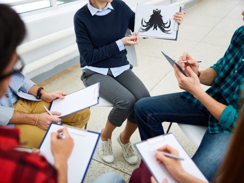 Female showing Rorschach inkblot to students during explanation